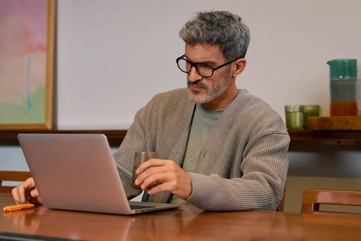 Homme portant des lunettes et travaillant avec concentration sur un ordinateur portable